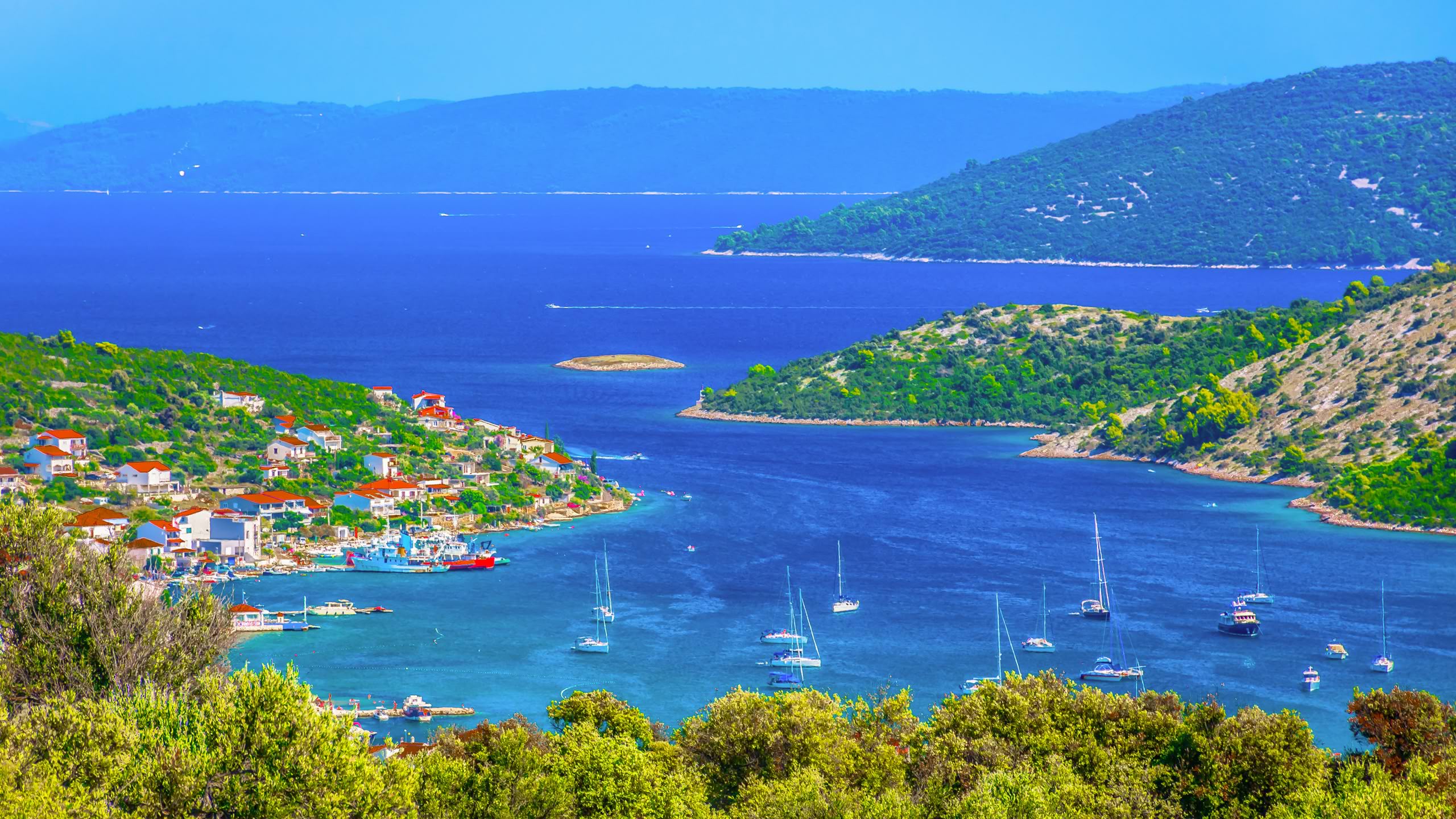 Segelbåtar i en turkos vik vid en kustby i Kroatien