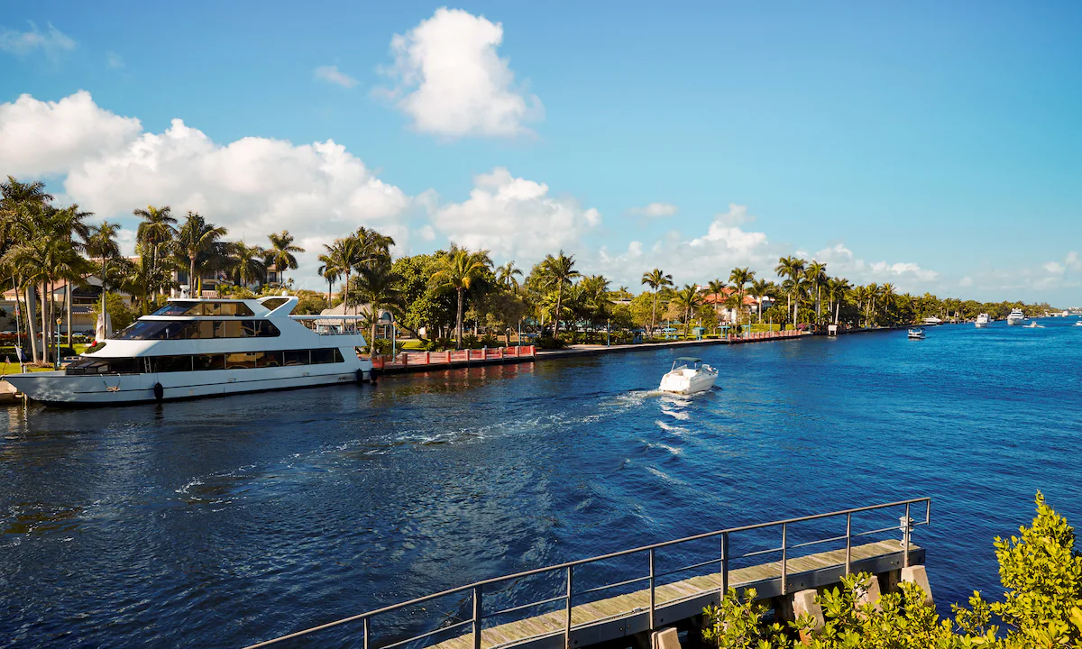Yacht och motorbåt på kanal kantad av palmer i Florida