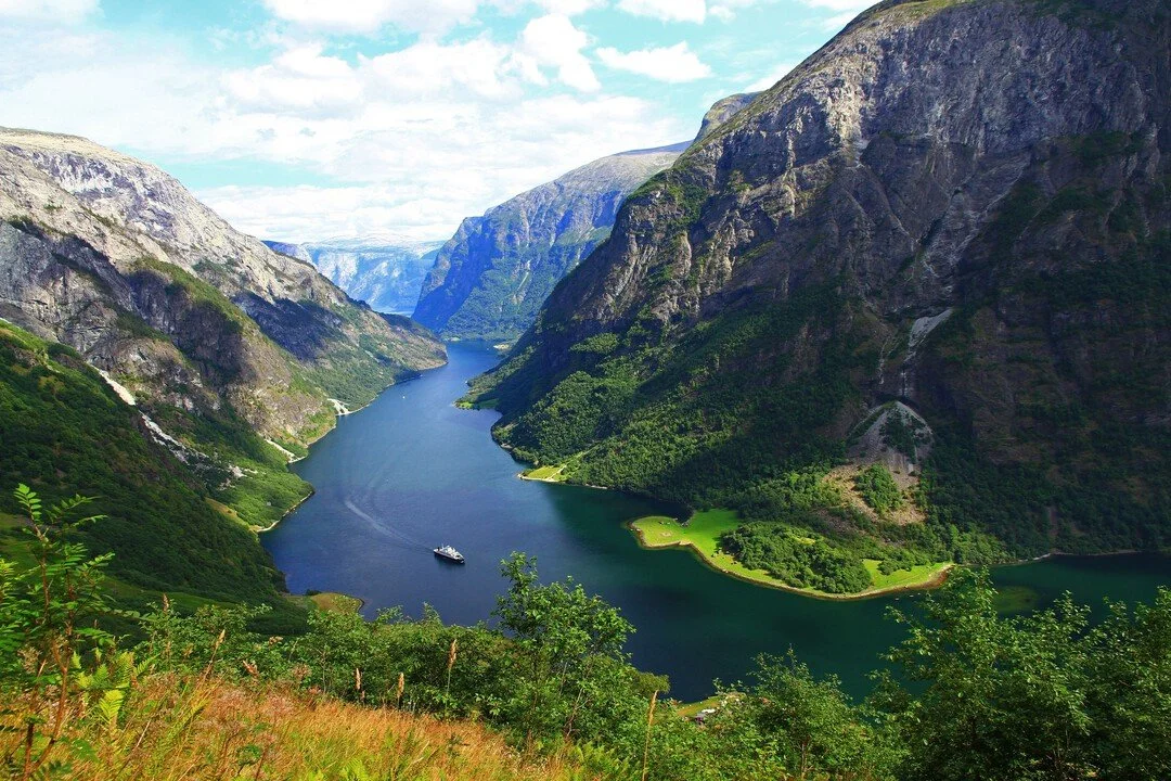 Elegant yacht i en norsk fjord omgiven av branta fjäll och vattenfall